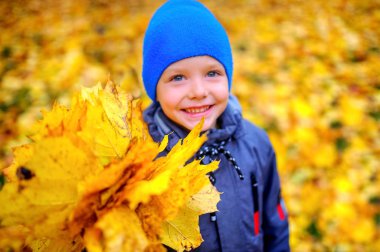 mutlu çocuk gülümseyen ve sonbahar yaprakları bir buket tutan