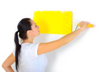 kadın ressam bir rulo ile duvar parlak sarı renkte boyar.