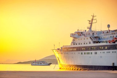 Büyük bir kargo çıplak bir tekne limana yelken zemin karşı parlak bir günbatımı üzerinde duran liman gemi