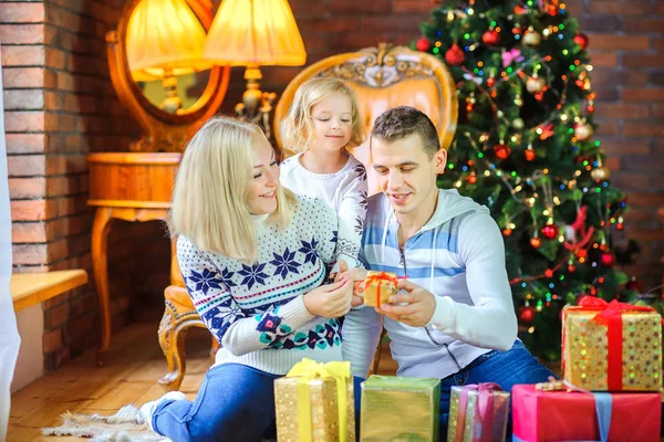 クリスマス ツリーの近くの床の上に座って幸せな家族を祝福してお互いに贈り物を与える — ストック写真
