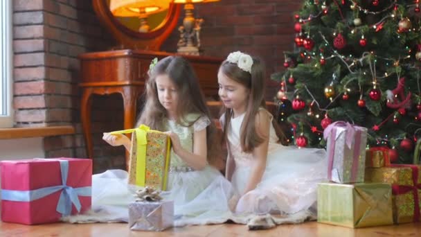 Smukke Piger Kjoler Sidder Gulvet Nær Det Festlige Juletræ Giver – Stock-video