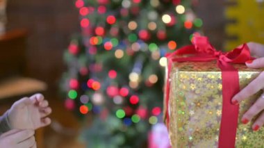 Anne kızı, bir Noel ağacı arka plan üzerinde bir hediye verir