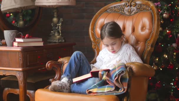 Dívka Sedí Židli Zájmem Čtení Pohádek Poblíž Zdobené Vánoční Strom — Stock video