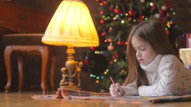 arka plan Noel ağacı Noel Baba'ya bir mektup yazma odasında yerde yatan küçük kız