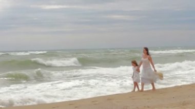 Annem ve onun sevgili kızı deniz kıyısı el ele tutuşarak ve eğleniyor yürüyor