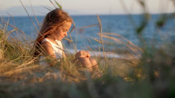 Liten Flicka Som Sitter Gräset Vid Havet Leker Med Kronblad — Stockvideo