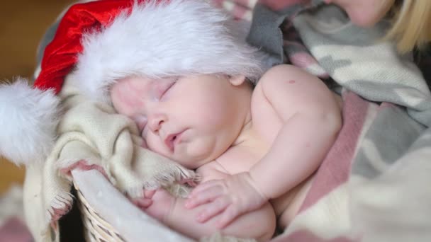 クリスマス バスケットに横たわって眠っているサンタ クロースの帽子で生まれたばかりの赤ちゃん — ストック動画