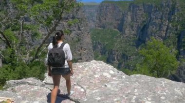 uçurumun kenarına gelen bir sırt çantası ile kız, görkemli kanyon bakarak