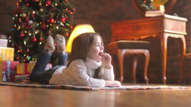 küçük kız yerde yatarken hayal ve Noel Baba'ya bir mektup yazma
