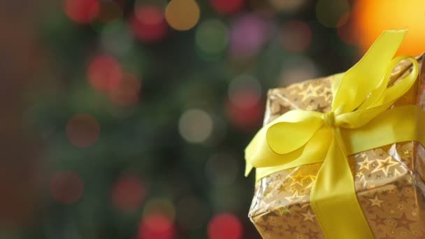 雌性手打开礼品盒 从礼品盒上取下黄色缎带 背景上明亮的节庆花环 — 图库视频影像