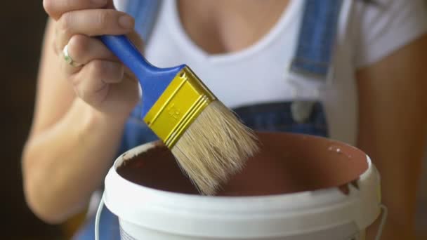 Nahaufnahme, professionelles Malermädchen befeuchtet Pinsel mit Farbe, bereitet sich auf das Malen vor