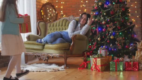 お祝いの驚き 女の子はお母さんが眠るときに木の下に贈り物を置きます クリスマスの夜 — ストック動画