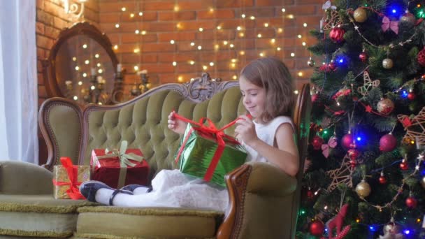 Prázdniny Šťastná Dívka Šatech Sedí Pohovce Blízkosti Vánočního Stromečku Otevírá — Stock video