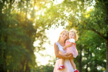 gün batımında güzel bir parkta kollarında küçük kızı ile anne