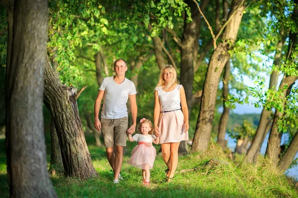 Happy family walks in a beautiful spring park, holding hands and smiling, healthy outdoor recreation
