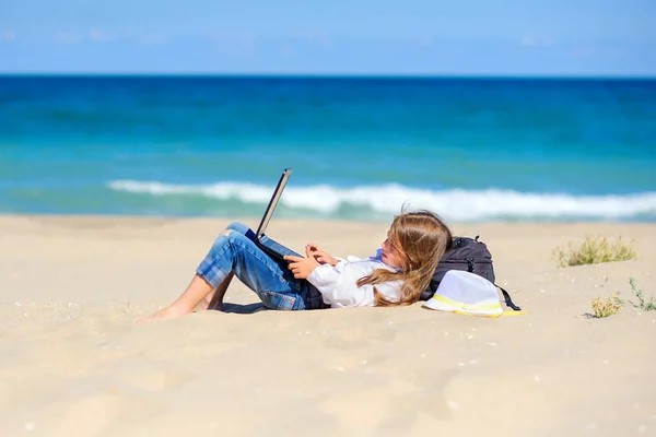 work in travel, a teen girl lies on the beach with a laptop. freelance