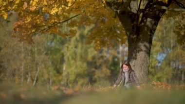 Autumn Park 'ta Paltolu Mutlu Kız Eğleniyor. Çocuk Düşmüş Yaprak 'ı Atıyor ve Çalıyor. Çocuklar açık havada eğleniyor. çocukluk kavramı.