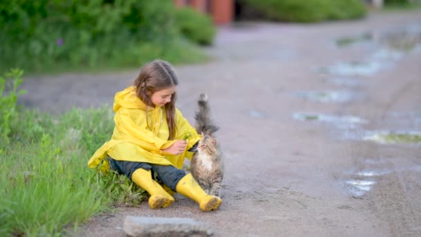 Šťastné Dítě Žlutém Plášti Botách Sedí Trávě Hraje Kočkou — Stock video