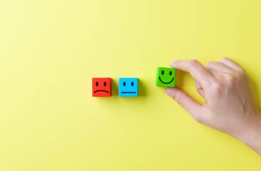 Müşteri memnuniyeti ve geri bildirim konsepti. Anket, geri bildirim derecesi, duygu, kullanıcı deneyimi ve hizmet değerlendirmesini temsil eden, üzgün ve nötr duygular arasında el seçimi yeşil mutlu yüz bloğu.