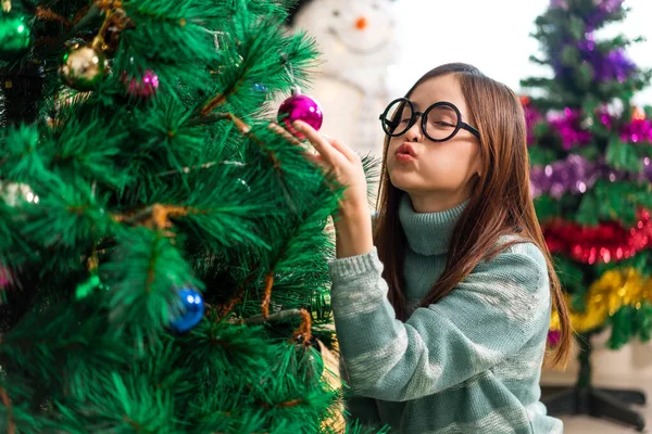 Mutlu Asyalı kadın portresi eğlenceli aktiviteler yapıyor Noel ağacını süslerken evde Noel arifesi, şenlik ve etkinlik kutlaması yapıyor.