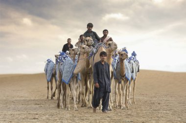 Al Madina, United Arab Emirates, July 22, 2017: men with camels in Rub Al Khali Desert. clipart