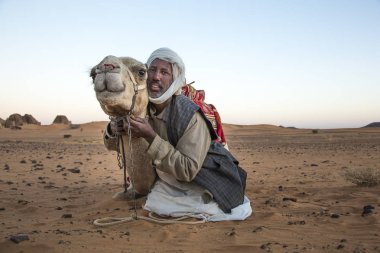 Meroe Pyramids, Sudan- 19th December, 2015: a man with his camel in a desert clipart
