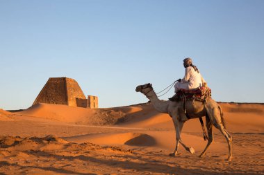 Meroe Pyramids, Sudan- 19th December, 2015: a man with his camel in a desert clipart