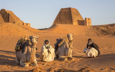 Meroe Pyramids, Sudan- 19th December, 2015: sudanese men on their camels in a desert of Sudan clipart