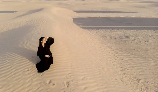 woman in a traditional emirati dress called abaya in a desert near Dubai