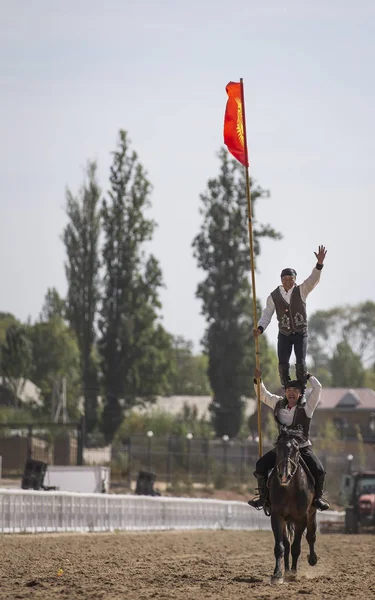 2018 日イシククリ湖 キルギスタン キルギスタンの旗を持った馬に乗って若い男性トリック — ストック写真