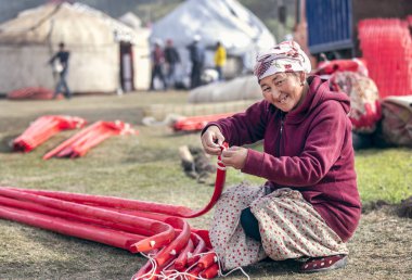 KYRCHYN, KYRGYZSTAN - SEPTEMBER 6TH, 2018: Kirghiz woman packing a yurt after World Nomad Games event clipart