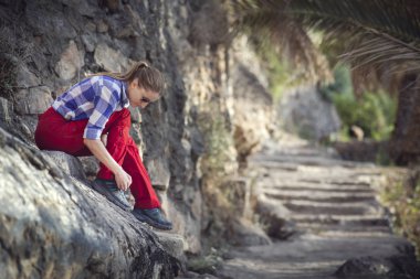 young female hiker lacing up shoes in old omani garden clipart