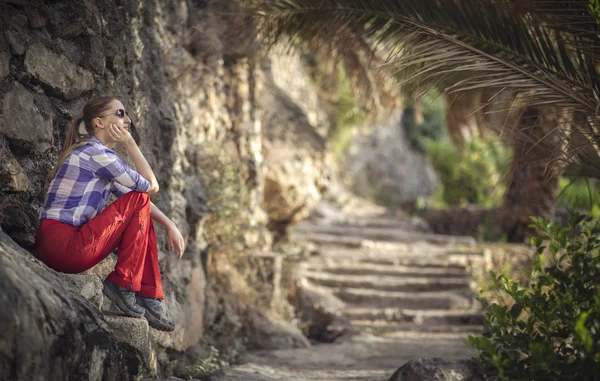 side view of young female hiker sitting in old omani garden and looking away