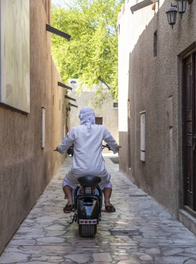 Al Seef, Dubai, Unated Arap Emirlikleri - 18 Kasım 2018: arkadan görünüm bir adam sokakta motosiklet sürüş