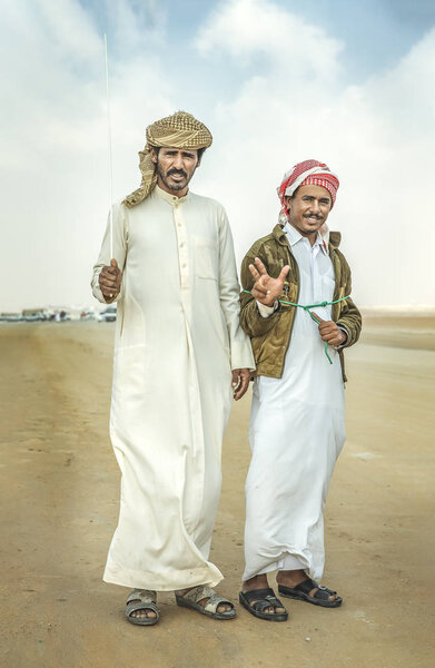 Madinat Zayed, United Arab Emirates - 22nd December, 2018: bedouins walking at Million Street in desert and looking at camera