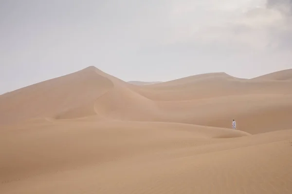 阿拉伯联合酋长国 Madinat Zayed 2018年12月22日 身穿传统阿联酋服装的男子在利瓦沙漠的巨大沙丘中行走 — 图库照片