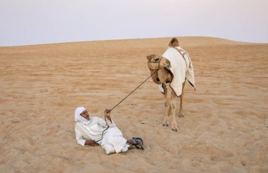Madinat Zayed, Birleşik Arap Emirlikleri, 22 Aralık, 2018: Arap adam onun deve çölde yakınındaki kum üzerinde yatan
