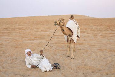 Madinat Zayed, Birleşik Arap Emirlikleri, 22 Aralık, 2018: Arap adam onun deve çölde yakınındaki kum üzerinde yatan