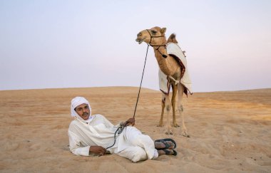 Madinat Zayed, Birleşik Arap Emirlikleri, 22 Aralık, 2018: Arap adam onun deve çölde yakınındaki kum üzerinde yatan