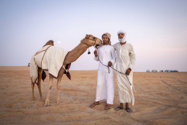 Madinat Zayed, Birleşik Arap Emirlikleri, 22 Aralık, 2018: çölde deve ile ayakta Arap erkekler