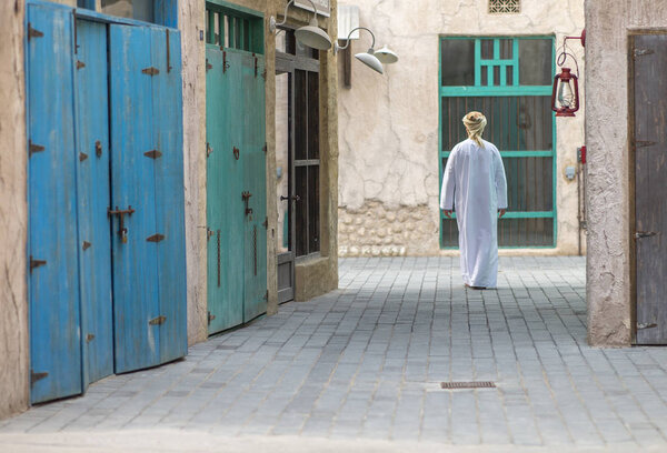 arab man in traditional costume walking in old Al Seef part of Dubai, United Arab Emirates