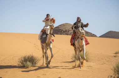 Meroe, Sudan - 19th December, 2015: happy Sudanese boys on their camels in desert clipart