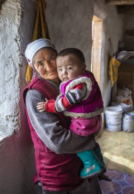 Bayan Olgii, Moğolistan - 30 Eylül 2015: Moğol kazak göçebe büyükanne holding çocuk onun kucağına kış evin içinde