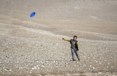Bayan Ulgii, Mongolia - 30 September 2015: mongolian kazakh nomad boy playing with flying disc clipart