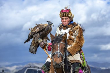 Bayan Ulgii, Moğolistan, 3 Ekim 2015: Geleneksel paltolu kazak adam ve at üzerinde kartalı ile şapkalı kazak adam