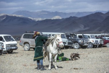 Bayan Ulgii, Moğolistan, 3 Ekim 2015: Geleneksel palto lu kazak adam ve atıyla doğadaki bir otoparkta şapkası