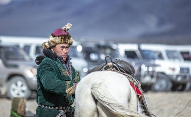 Bayan Ulgii, Moğolistan, 3 Ekim 2015: Geleneksel palto lu kazak adam ve atıyla doğadaki bir otoparkta şapkası