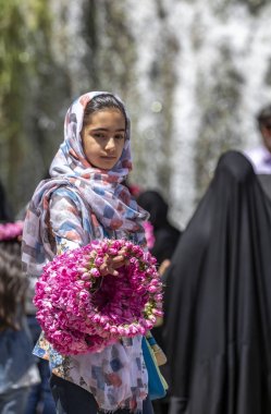 Niasar, Iran - 25th April, 2019: Iranian young girl with flowers, selling them to passersby during rose picking season clipart