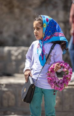 Niasar, İran - 25 Nisan 2019: Çiçekli İranlı genç kız, gül toplama mevsiminde yoldan geçenlere satıyor
