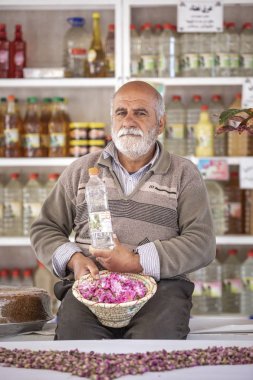 Keşan, İran - 25 Nisan 2019: Gül suyu satan dükkanda gül yaprakları olan İranlı adam
